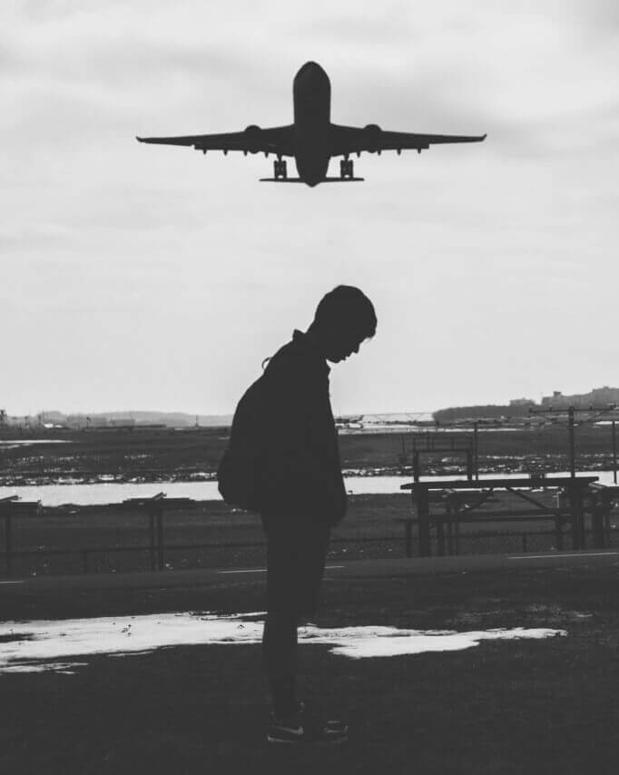 Plane flies over a sad man in a long distance relationship