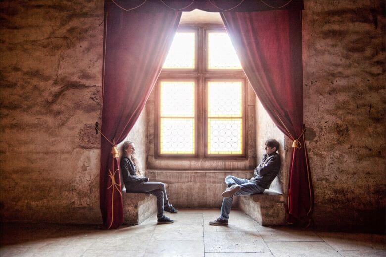 Guy and girl speaking a foreign language under red curtains