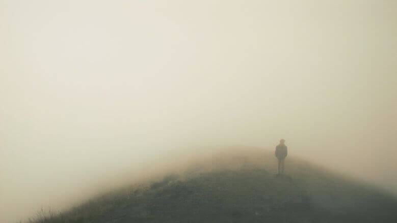 Man standing on a hill in the fog