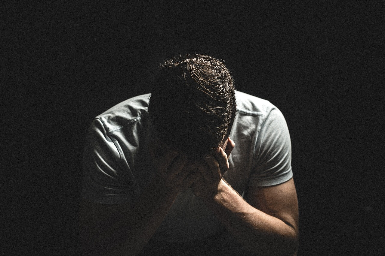 Vulnerable man with head in hands