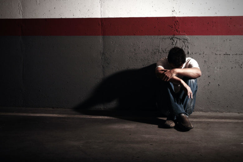 Sad man sitting by wall