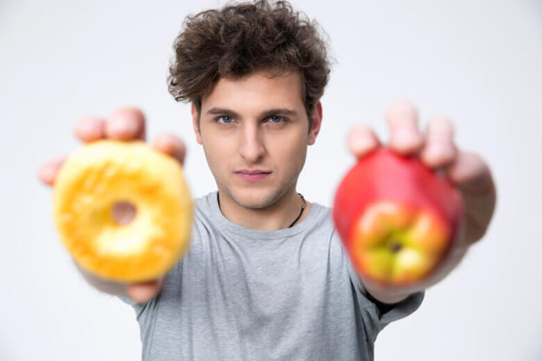Man holding apple and donut